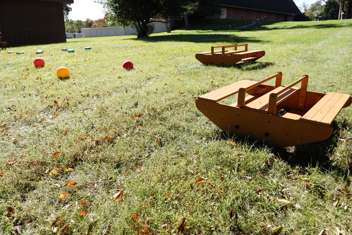 Wooden rocking boats and play balls on the grass at Newark Nature School, Newark, DE
